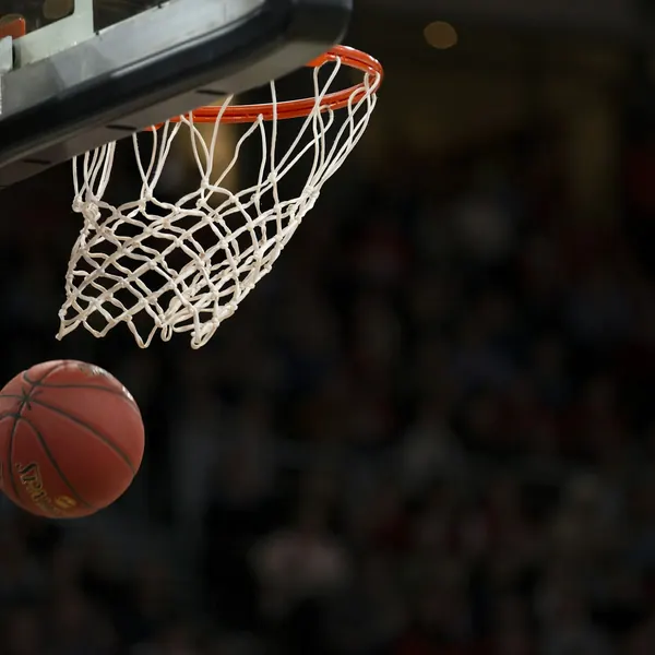 Balón de básquetbol cayendo por el aro